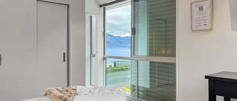 A modern bedroom with a large window, a bed with a fur throw, and a view of the outdoors.