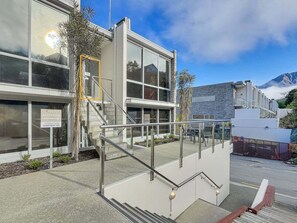 A modern building with a reception desk, a staircase, and a view of mountains.