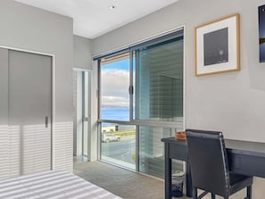 Ein modernes Zimmer mit großem Fenster, Schreibtisch und Stuhl.