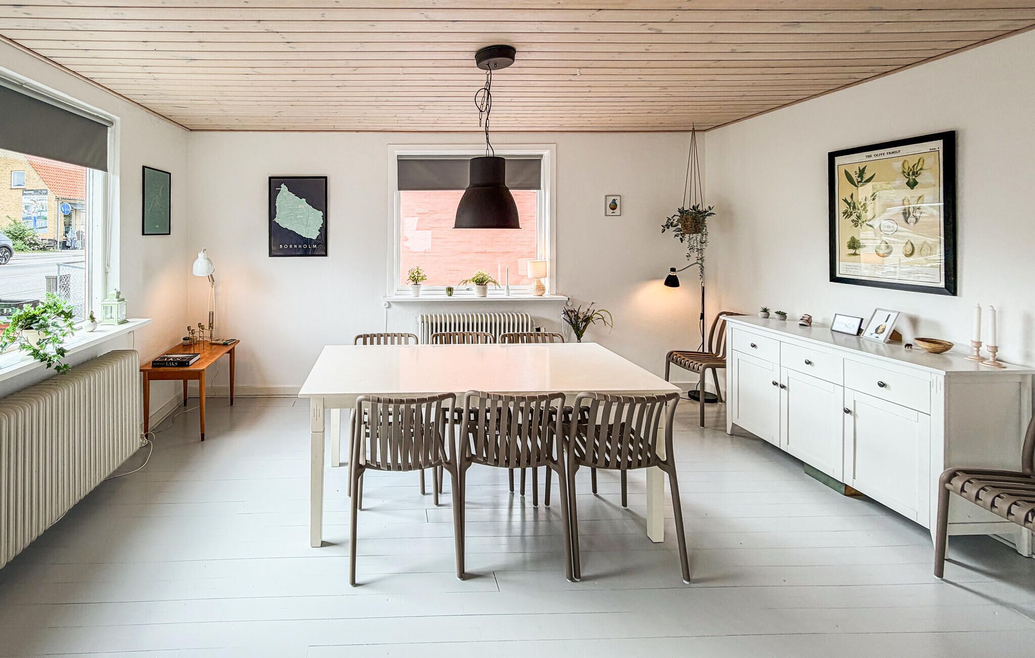 A modern kitchen with a white table, chairs, and a hanging light fixture.