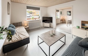 A modern living room with a sofa, a coffee table, a TV, and a dining area with a table and chairs. - Beautiful home in Allinge with WiFi (Allinge)