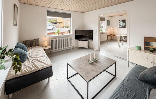 Ein modernes Wohnzimmer mit einer Couch, einem Couchtisch, einem Fernseher und einem Essbereich mit Tisch und Stühlen.