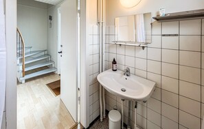 Ein Badezimmer mit weißem Waschbecken, Spiegel und gefliesten Wänden.