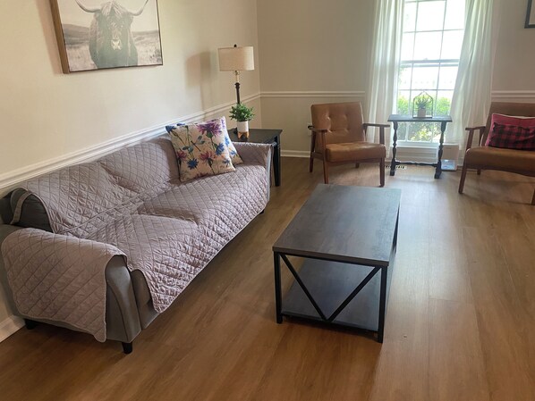 Un salon avec un canapé, une table basse et deux fauteuils.