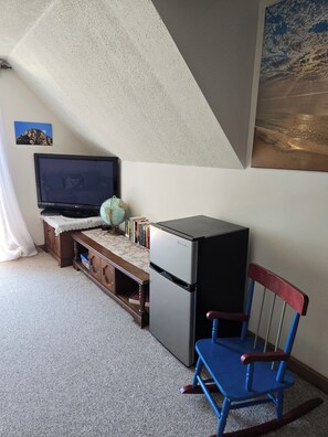 Huoneessa on televisio, pieni jääkaappi, maapallo ja sininen tuoli.