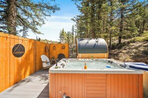 Ett bubbelbad med en trädeck, en överbyggd grillplats och ett trästaket med en logotyp.