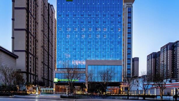 A Holiday Inn Express hotel with a modern glass facade, surrounded by other high-rise buildings.