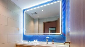 A modern bathroom with a large mirror, a sink, and a towel rack.