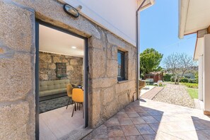 A stone exterior wall with a door leading to an interior space with a sofa and chairs. - GuestReady - Courtyar 9/99 - Apt 05 (Porto)