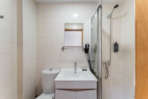 Un baño pequeño con inodoro, lavamanos y ducha.
