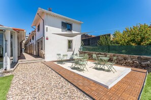 A white building with a patio area, outdoor seating, and a stone wall. - GuestReady - Courtyar 9/99 - Apt 7A (Porto)