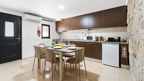 A modern kitchen with a dining table set for four, a microwave, a coffee maker, and a dishwasher. - GuestReady - Courtyar 9/99 - Apt 7A (Porto)