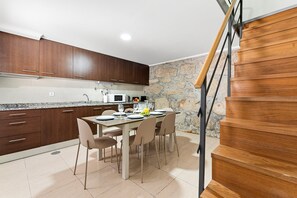 A modern kitchen with dark wooden cabinets, a granite countertop, and a dining area with a table set for four. - GuestReady - Courtyar 9/99 - Apt 7A (Porto)