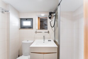 Casa de banho compacta com sanita, lavatório e chuveiro.