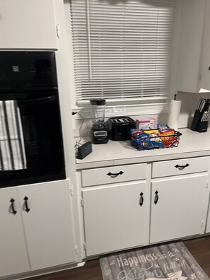 A kitchen with a blender, toaster, and snack packets on the counter.