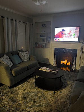 A living room with a sofa, a coffee table, a fireplace, and a television.