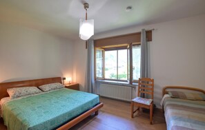 A bedroom with a bed, a chair, a nightstand, a window with curtains, and a radiator. - Awesome apartment in Rocca with WiFi (Rocca)