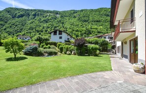 Ein Innenhof mit Rasenfläche, einem gepflasterten Weg und einem Gebäude mit Balkon.