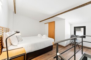 Ein modernes Hotelzimmer mit Bett, Nachttisch, Lampe und Sessel.