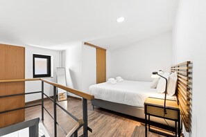 Ein modernes Hotelzimmer mit Bett, Nachttisch und Holz-Kopfteil.