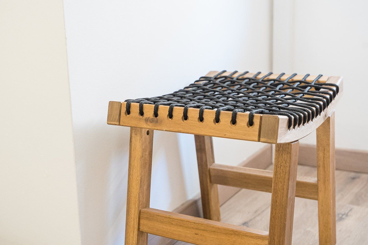 A wooden stool with a woven seat.