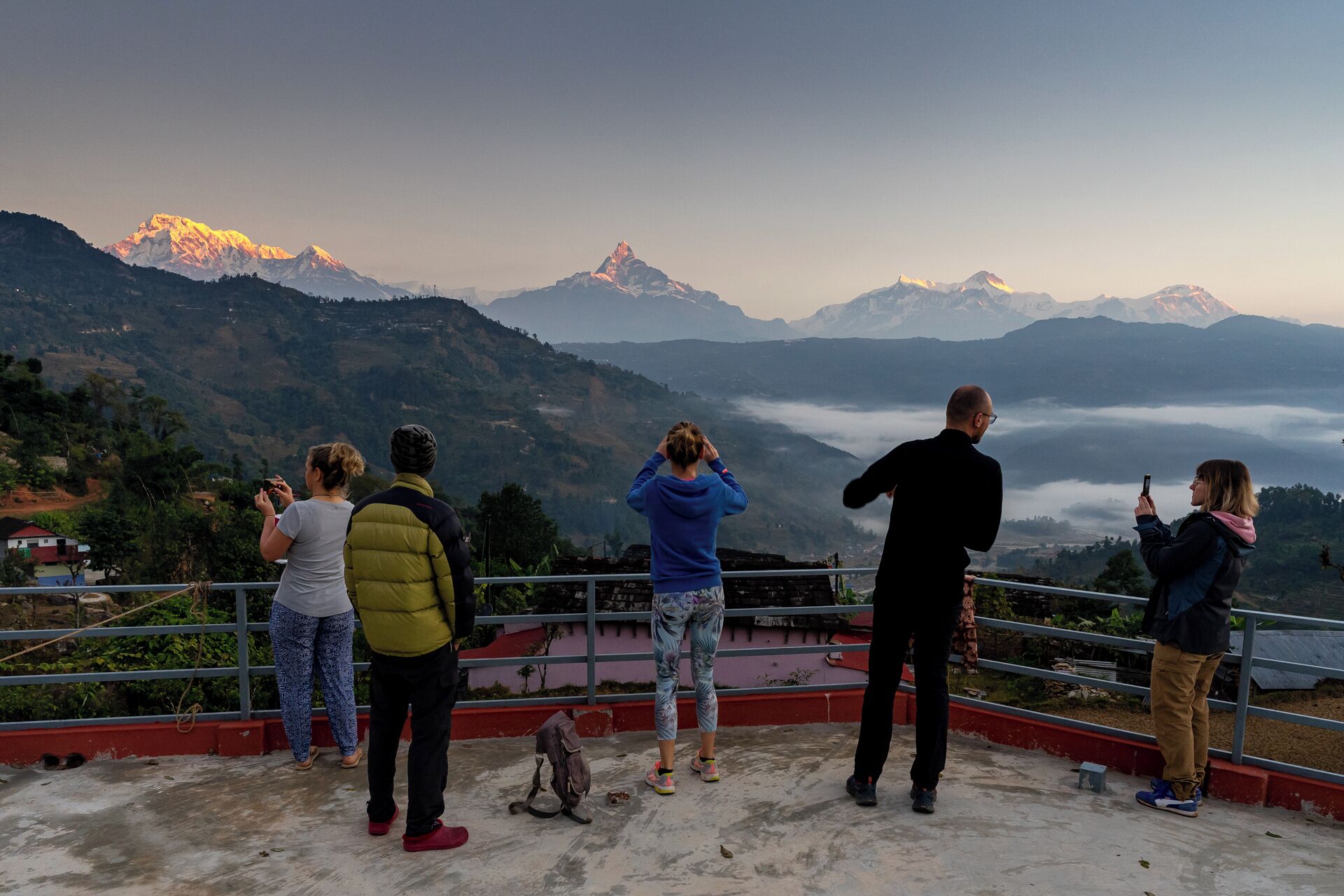 Eine Gruppe von Menschen auf einem Dach mit Blick auf eine gebirgige Landschaft.