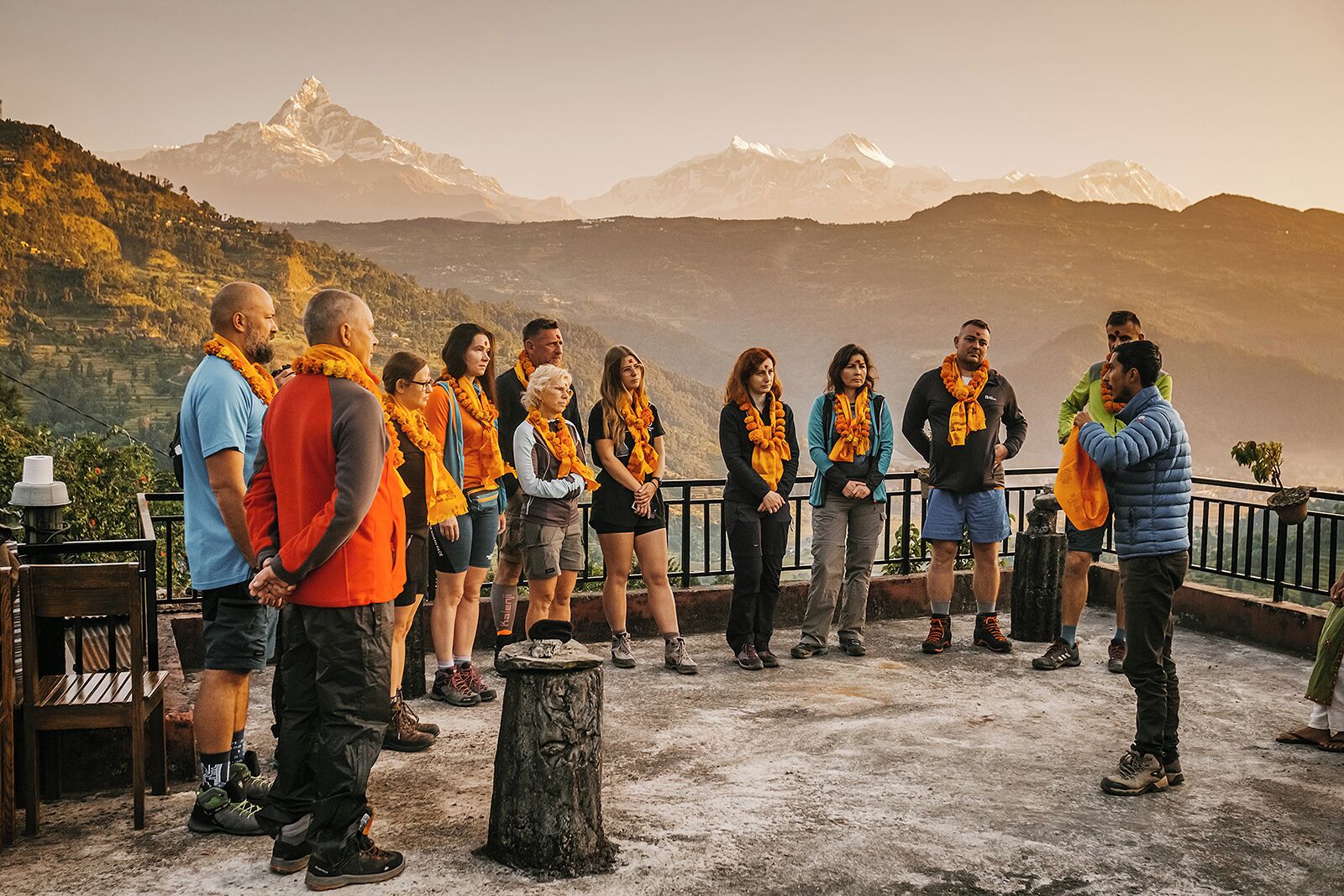 A group of people standing on a terrace with a mountainous backdrop.