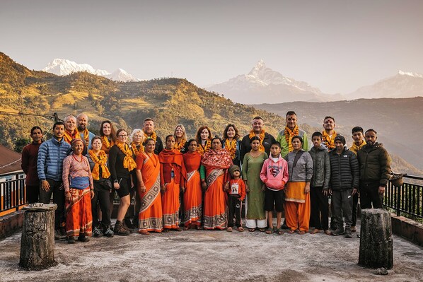 A group of people standing on a concrete platform with a mountainous landscape in the background.