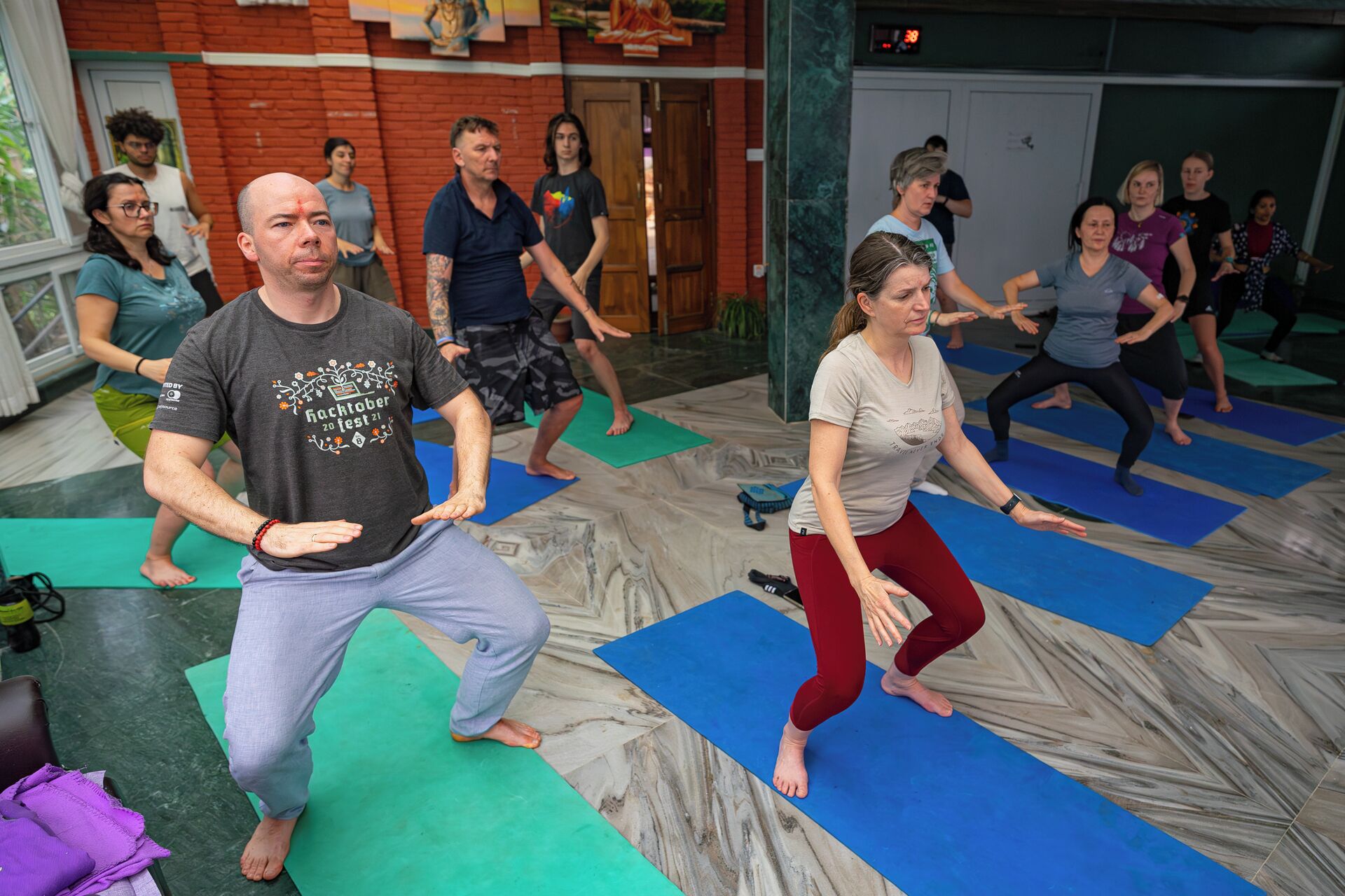 A group of people exercising on mats in a room with a marble floor and a brick wall.