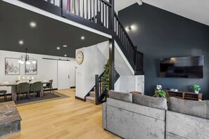 A modern living room with a staircase, a dining area, and a flat-screen TV. - CanaanValley Views! FirePit - Arcade - ResortAmenities (Davis)