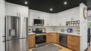Una cocina moderna con electrodomésticos de acero inoxidable, armarios de madera y techo negro.