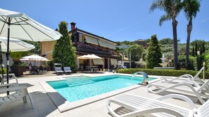 A swimming pool with lounge chairs, umbrellas, and a building with a balcony in the background. - Awesome apartment in Castellabate (Castellabate)