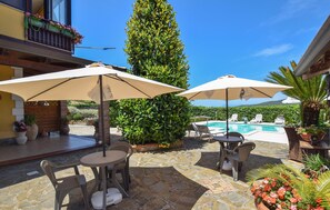 A patio area with stone flooring, outdoor seating, umbrellas, a pool, and a tall green hedge. - Awesome apartment in Castellabate (Castellabate)