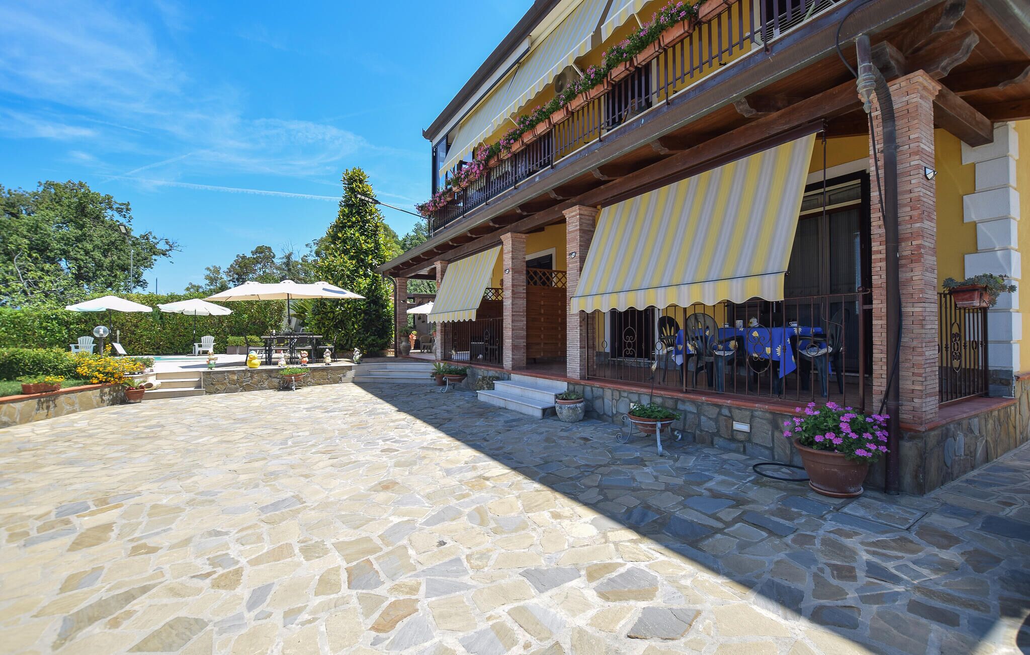 A courtyard with stone flooring, outdoor seating, and a pool.