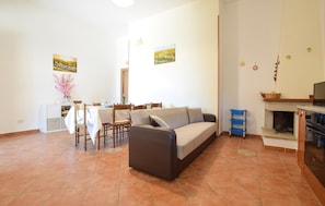 A living room with a sofa, dining table, chairs, and a fireplace. - Awesome apartment in Castellabate (Castellabate)