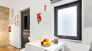 Eine moderne Küche mit weißen Schränken, einem Esstisch mit Stühlen, einem Fenster mit Aussicht und einem Feuerlöscher an der Wand.