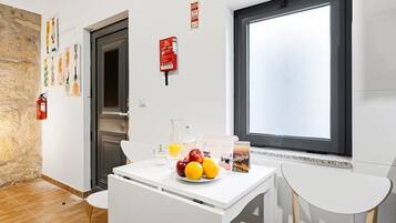 Eine moderne Küche mit weißen Schränken, einem Esstisch mit Stühlen, einem Fenster mit Aussicht und einem Feuerlöscher an der Wand.