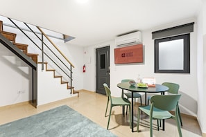 Ein modernes Interieur mit einer Treppe, einem Essbereich mit Stühlen und einem Tisch sowie einem Schild mit der Aufschrift 'GUEST READY'.