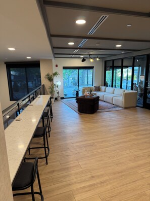 Een moderne hotellobby met een lange balie, een zithoek en grote ramen.