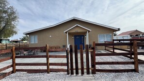 A building with a blue door, a wooden fence, and outdoor seating.
