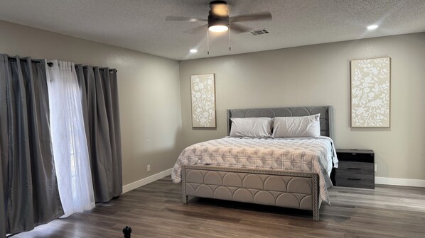 A bedroom with a bed, a nightstand, a ceiling fan, and two wall-mounted light fixtures.