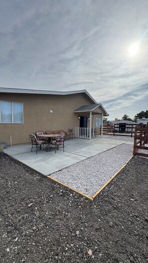 A building with a patio area, outdoor furniture, and a gravel driveway.