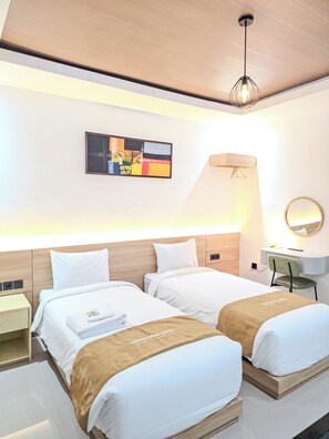 A hotel room with two beds, a desk, a chair, a lamp, a mirror, and a painting on the wall. - Lodji Svarga Premiere Villa (Sleman)