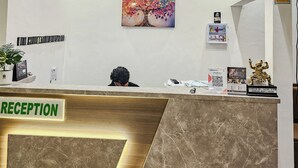 A reception area with a marble counter, a 'RECEPTION' sign, a colorful tree painting, a hanging lamp, and a statue.
