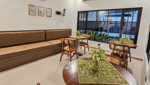 A modern interior with a seating area, a round table with a patterned tablecloth, and a large window with a view.