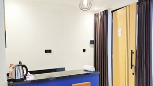 A kitchen with a blue counter, wooden stools, a hanging light fixture, and a door with curtains.