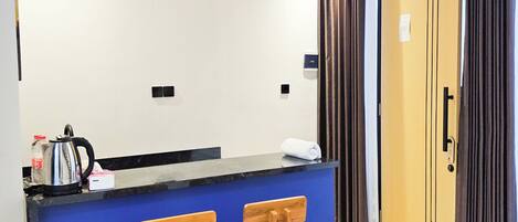 A kitchen with a blue counter, wooden stools, a hanging light fixture, and a door with curtains.