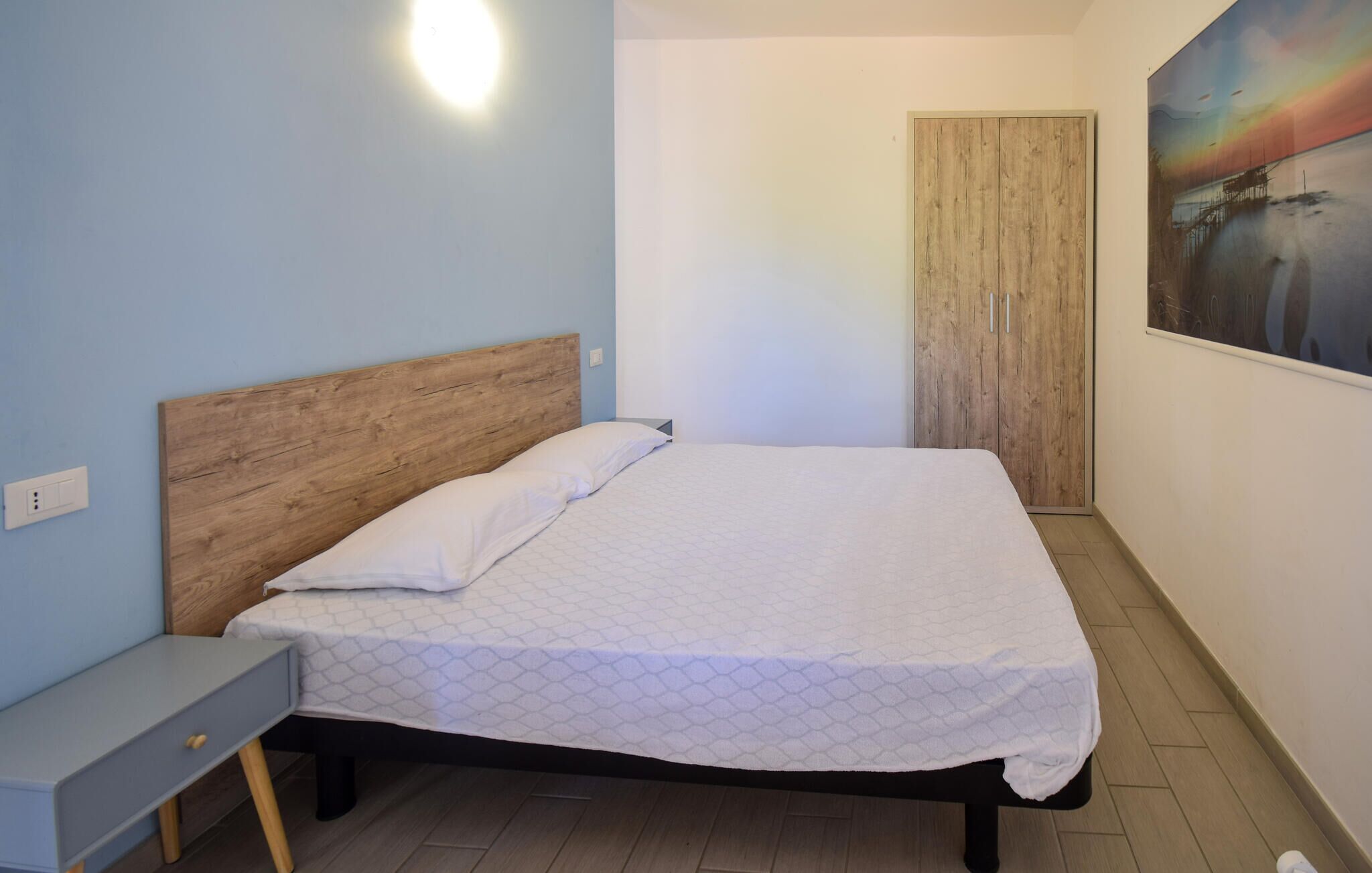 Ein Schlafzimmer mit einem hölzernen Kopfteil, einem Einzelbett, einem Nachttisch und einem Kleiderschrank.