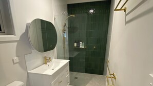 Un baño con inodoro, lavabo, espejo, ducha y toallero.