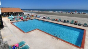 Una piscina con sillas de descanso y vistas a la playa.